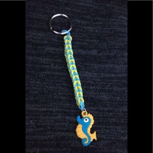 A blue and yellow keychain with a seahorse charm